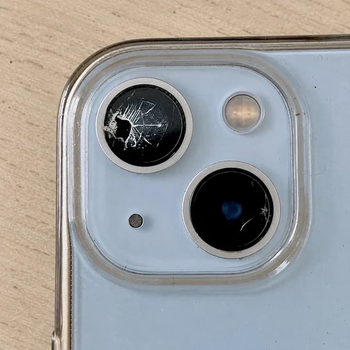Bližnji pogled na počeni zaščitni stekli kamer svetlo modrega iPhona.